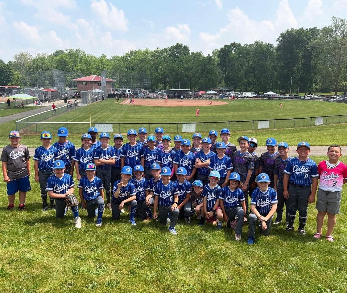 Youth Cubs baseball team posed on the outfield grass in pinstripe jerseys